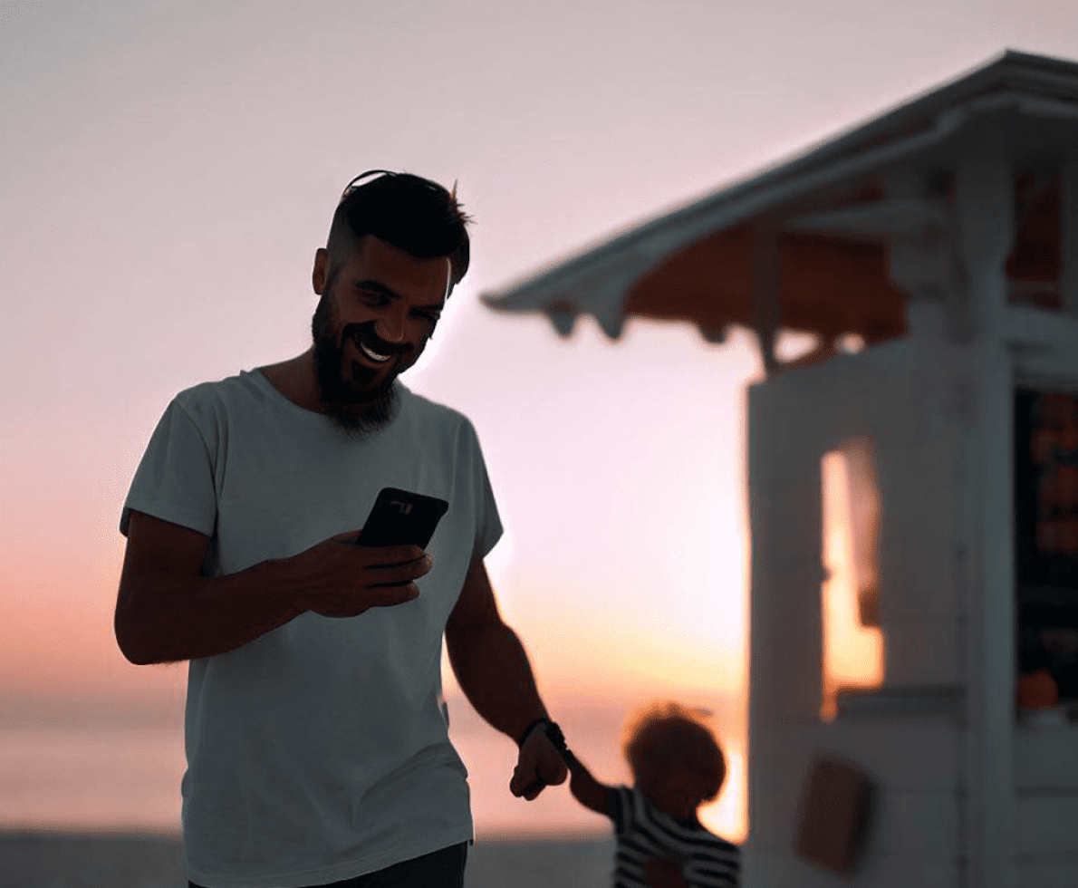padre con su hijo de la mano feliz y mirando el móvil